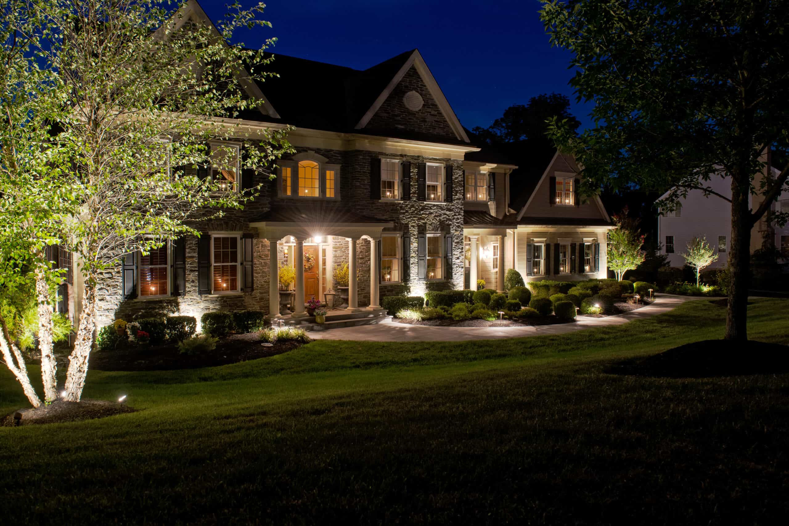 front of home lit up at night- Benefits of Outdoor Lighting - Burkholder Landscape