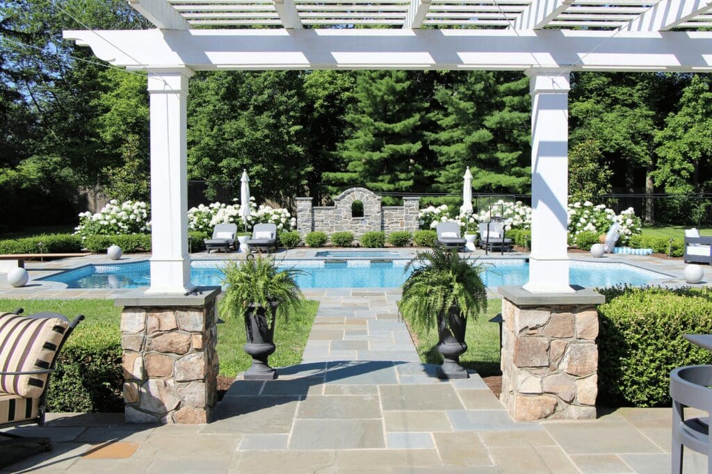 White pergola and walkway leading to pool area- Burkholder Landscape