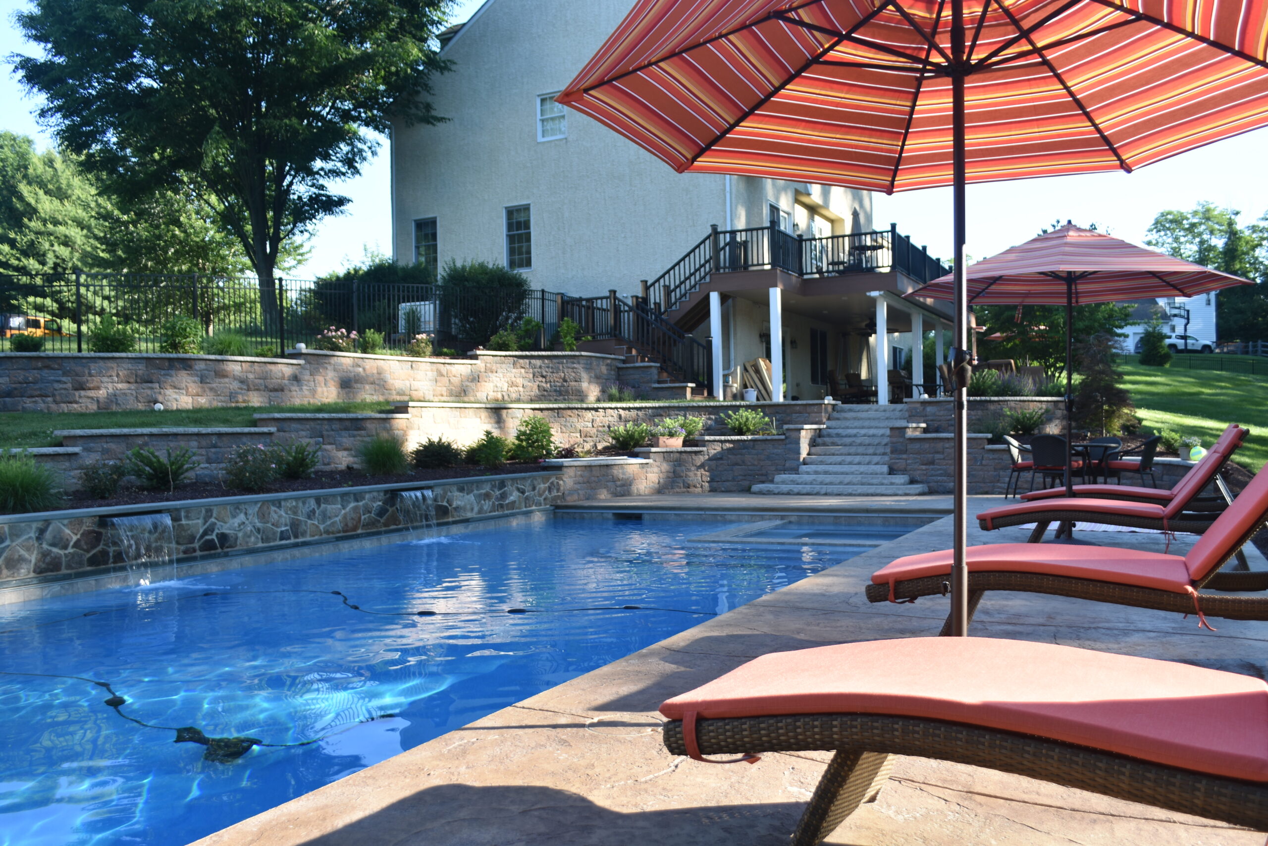 pool with chaise lounges and umbrella - investing in landscape design - Burkholder Landscape